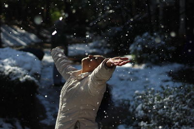 Woman with arms outstretched wearing warm clothing during winter