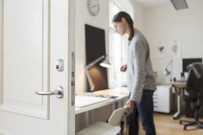 White open door against woman adjusting chair in creative office