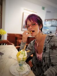 Portrait of young woman holding ice cream at home