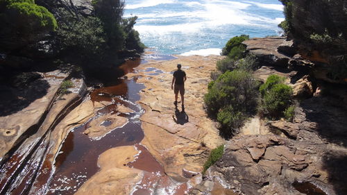 Man standing on rock by sea