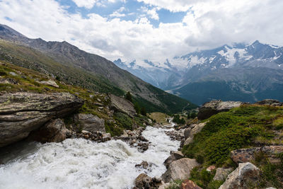 Scenic view of river flowing through valley against mountain range