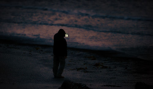 Silhouette woman standing on beach at sunset