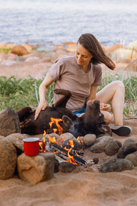 Side view of woman sitting on rock at beach