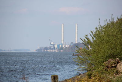 Factory by sea against sky