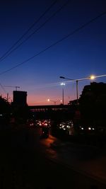 Illuminated city street against sky at night