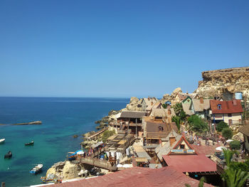 Houses by sea against clear blue sky