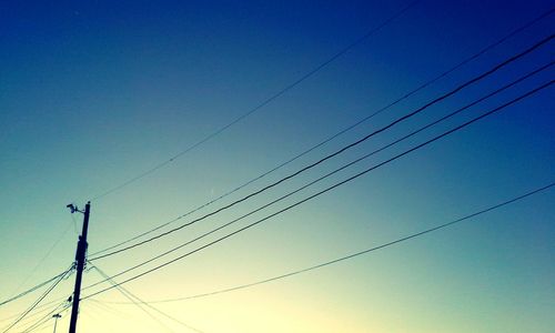 Low angle view of electricity pylon against blue sky