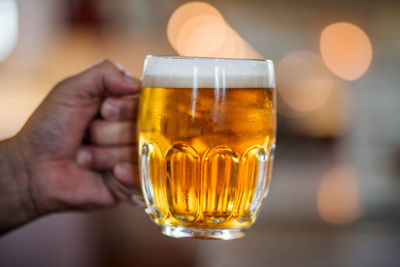 Close-up of hand holding beer glass