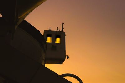 Low angle view of silhouette built structure against orange sky