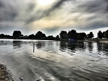 Silhouette ducks swimming on lake against sky