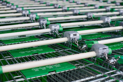 Row of parked trolleys in supermarket. many empty green shopping carts in row.