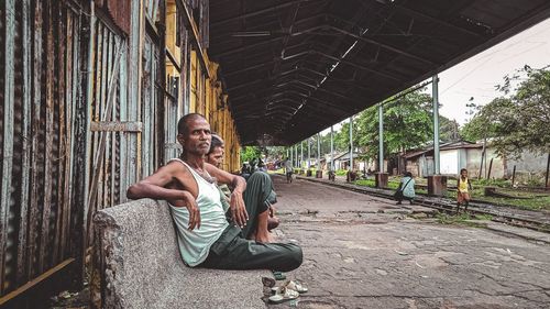 Full length portrait of young man sitting outdoors