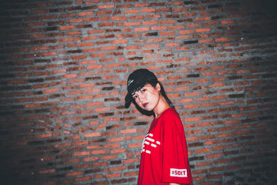 Portrait of smiling woman standing against red wall