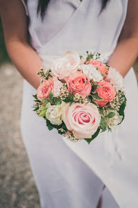 Midsection of bride holding rose bouquet