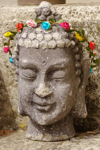 Close-up of buddha statue by stone wall