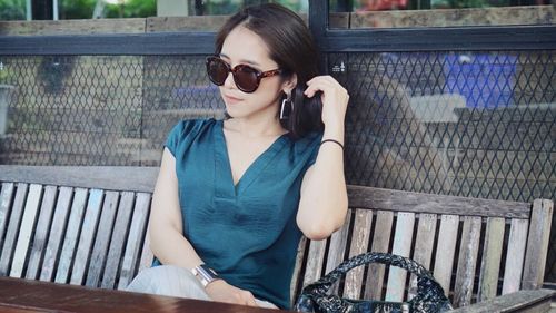 Young woman wearing sunglasses sitting on bench