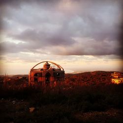 Abandoned building on field against sky during sunset