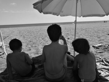 Rear view of siblings sitting on beach