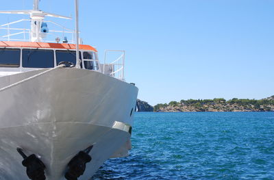 Boat sailing in sea against clear blue sky