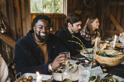 Portrait of smiling man enjoying with female and male friends during social gathering