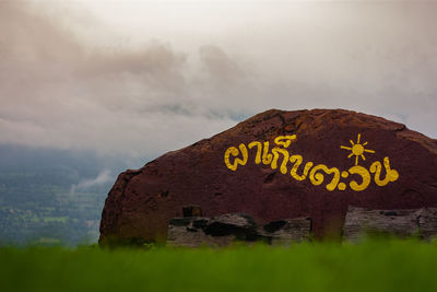 Information sign on rock against sky