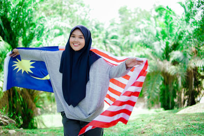 Muslim woman happy holding a malaysian flag. malaysia independence day.