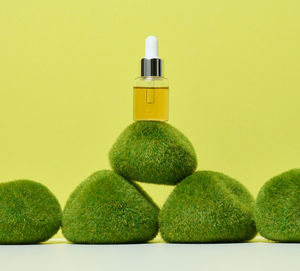 Glass transparent bottle with pipette and yellow oil on green moss. containers for acids, cosmetics
