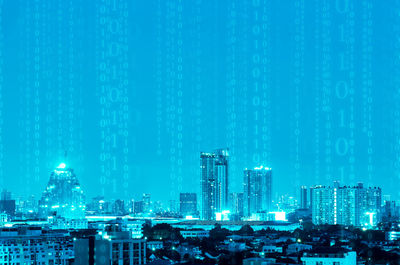 Illuminated buildings against blue sky at night