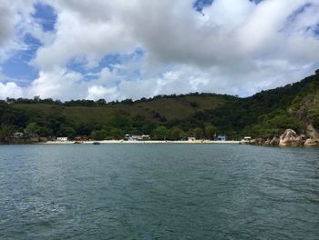 Scenic view of sea and mountains against cloudy sky