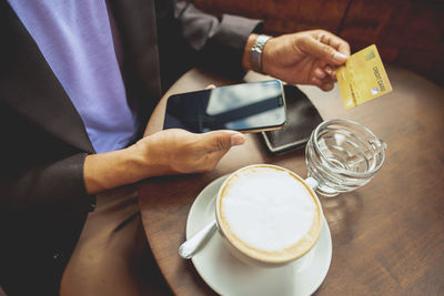 Midsection of man holding coffee cup on table