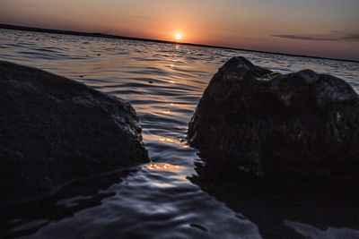 Close-up of beach against sky during sunset