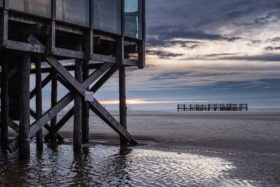 Pier over sea against sky during sunset