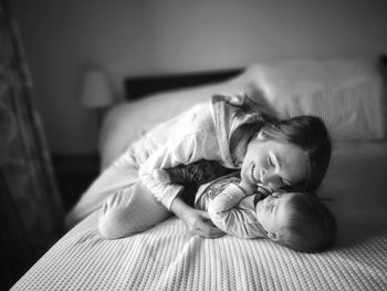 Smiling woman playing with son on bed at home