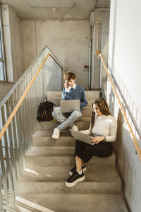 Programmers using laptops on steps in office