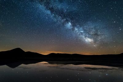 Scenic view of lake against mountains at night