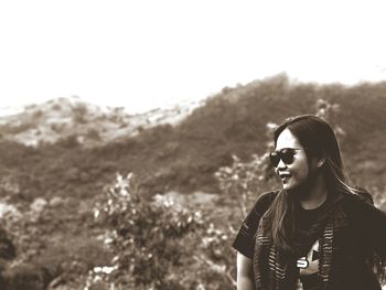 Young woman looking away against sky