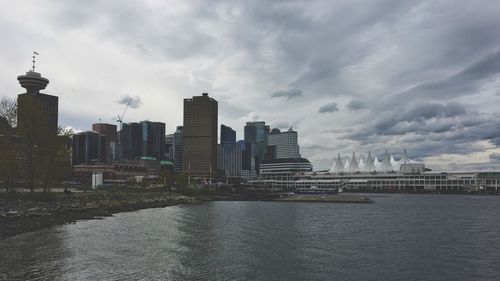 City at waterfront against cloudy sky