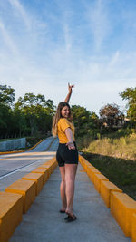 Full length of woman standing on road against trees