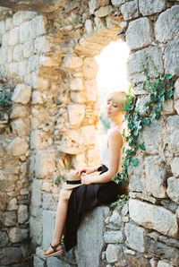 Portrait of young woman standing against old ruins