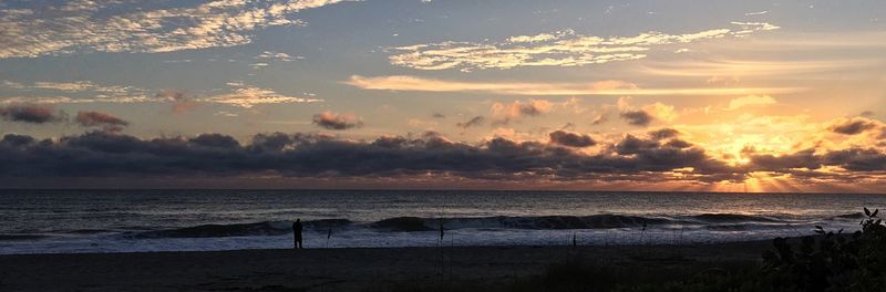 Scenic view of sea against dramatic sky during sunset