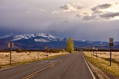 Empty road by mountains against sky