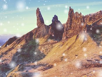 Winter sunrise over old man of storr, snowflakes in the air. abstract lighting, colorful flare.