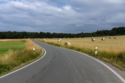 Road amidst field against sky