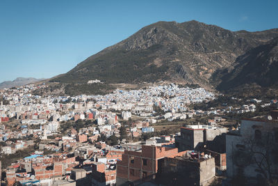 Aerial view of townscape by mountains against clear sky