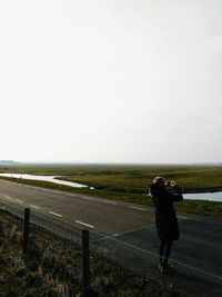 Full length of man photographing on landscape against sky