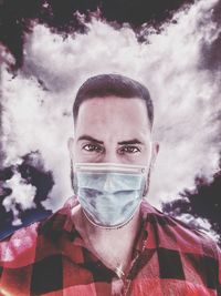 Portrait of young man covering face against sky