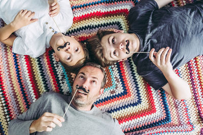 Directly above shot of family holding props while relaxing on bed