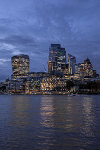 View of illuminated modern financial district skyscrapers from river thames