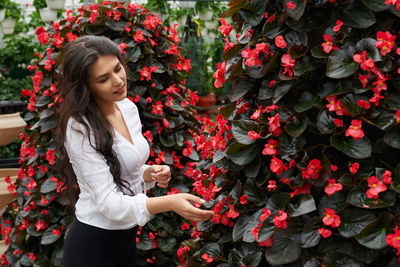 Beautiful young woman standing by flowering plants