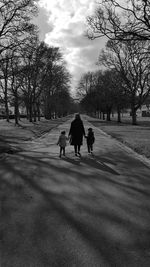 Rear view full length of mother walking with children on road